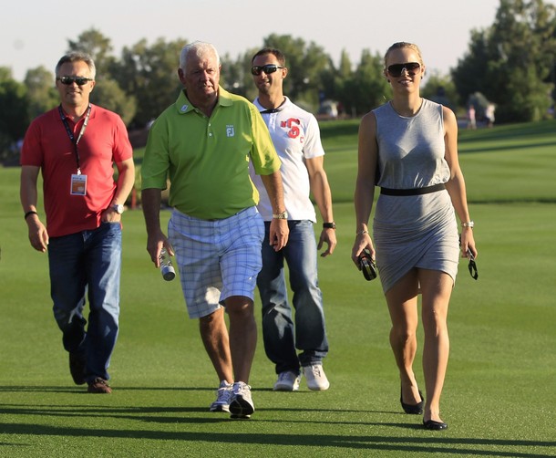 Tennis player Wozniacki of Denmark walks at the 18th hole with her father Piotr and Gerry, the father of McIlroy of Northern Ireland, during the third round of the Dubai World Championship in Dubai